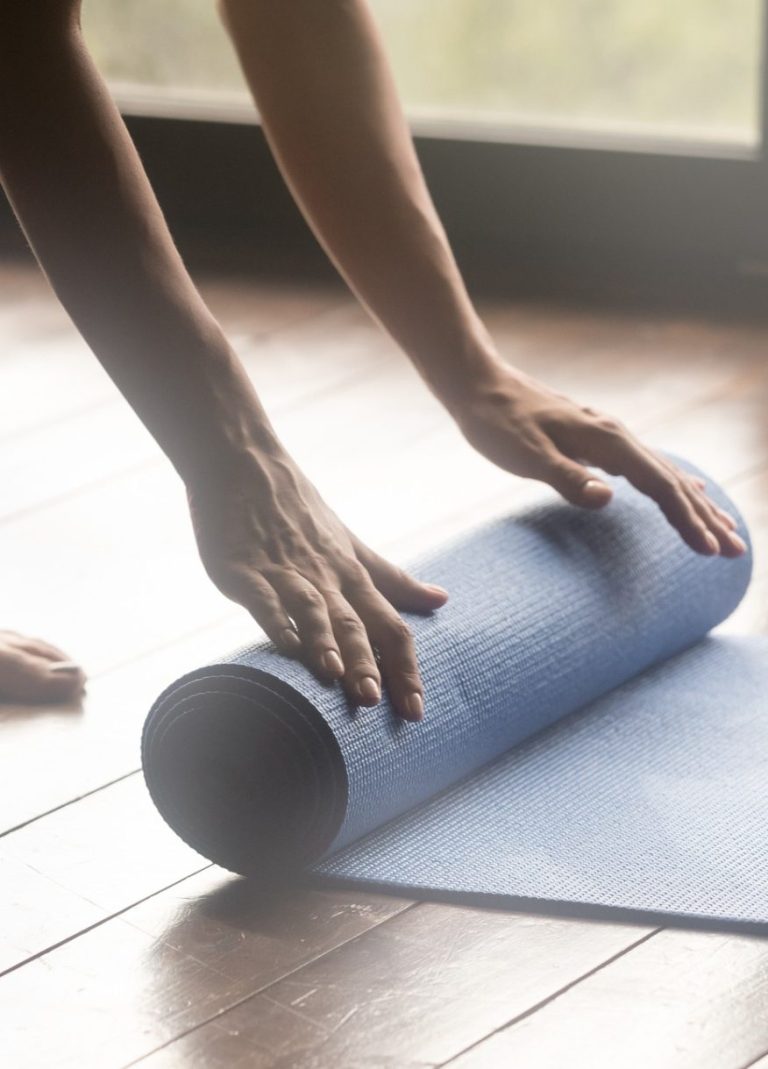 Frau rollt Yogamatte aus